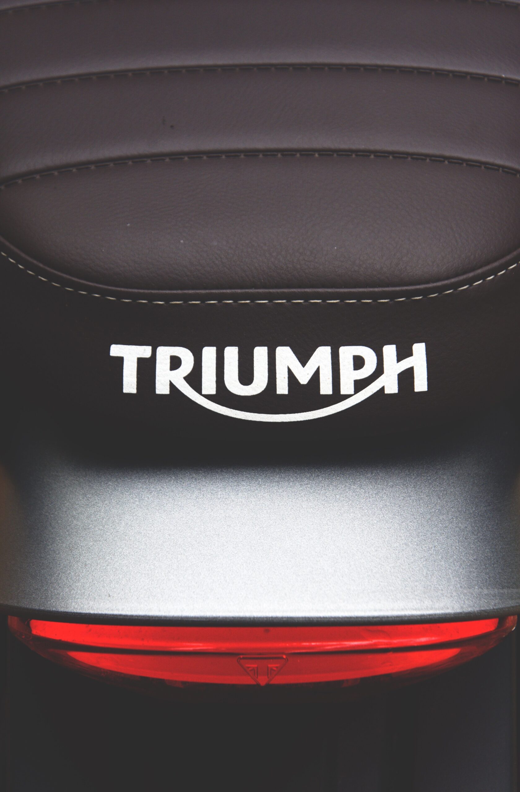 Detailed view of a Triumph motorcycle seat and logo, highlighting sleek design.